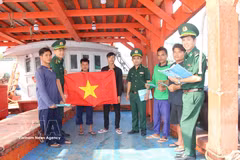 Officers and soldiers of the Ganh Hao border guard station present a national flag to fishermen before they head out to sea. (Photo: VNA)
