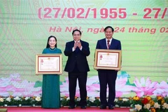 Prime Minister Pham Minh Chinh (C) presents the third-class Labour Order to Associate Professor Dr. Dao Xuan Co, Director of Bạch Mai Hospital, and the Meritorious Doctor title to Nguyen Thi Mai Ngoc, a doctor at the Vietnam National Heart Institute under Bach Mai Hospital. (Photo: VNA)