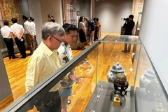 Visitors are captivated by the displays of rare antiques at the exhibition. (Photo: VNA)