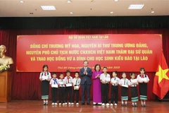 Chairwoman of the Vu A Dinh Fund Truong My Hoa and Vietnamese Ambassador to Laos Nguyen Minh Tam present scholarships to overseas Vietnamese students. (Photo: VNA)