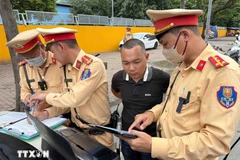 Traffic police officers present image evidence of a violation to a driver. (Photo: VNA)