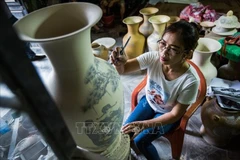 A worker creates patterns for Bat Trang ceramic products. (Photo: VNA)