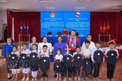 Vietnamese and Laos volunteers present gifts to disadvantaged students in Xekong province. (Photo published by VNA)