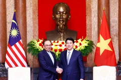 Vietnamese State President Luong Cuong (R) welcomes Malaysian Prime Minister Anwar Ibrahim. (Photo: VNA)