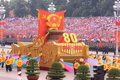 A model vehicle bearing the National Emblem of the Socialist Republic of Viet Nam leads the military parade and mass procession. (Photo: VNA)