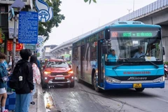 Passengers wait to board a bus in Hanoi (Photo: VNA). 