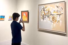 An art lover photographs a painting at the opening of the “Indonesia – Vietnam Art Dialogue” exhibition, which runs until June 5. (Photo courtesy of the gallery)