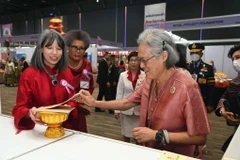 Ho Thi Thu Trang (left), spouse of the Vietnamese Ambassador to Thailand, invites Thai Princess Maha Chakri Sirindhorn to a lottery ticket of the bazaar. (Photo: VNA)