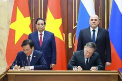 Vietnamese PM Pham Minh Chinh (standing, left) and his Russian counterpart Mikhail Mishustin (standing, right) witness the signing of the agreement between the two governments on cooperation in building a nuclear power plant on the territory of Vietnam. (Photo: VNA)