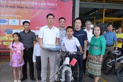 The head of the Nghe An entrepreneurs’ club in Naxaithong presents the gifts to a disadvantaged students at the ceremony. (Photo: VNA) 