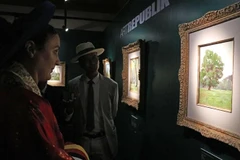 Amandine Dabat (left) - the fifth-generation descendant of King Ham Nghi and visitors contemplate paintings by King Ham Nghi. (Photo: VNA)