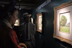 Amandine Dabat (left) - the fifth-generation descendant of King Ham Nghi and visitors contemplate paintings by King Ham Nghi. (Photo: VNA)