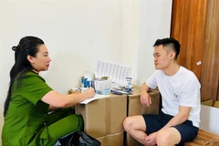 Pham Ngoc Tien is questioned by a police officer. (Photo: daibieunhandan.vn)
