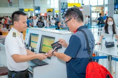 Aviation security personnel checks passenger' documents before he boards the plane. (Photo: VietnamPlus)