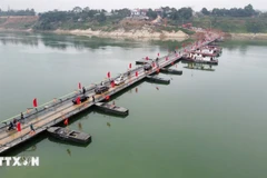 People and vehicles travel across the Lo river pontoon bridge on the morning of February 16. (Photo: VNA) 