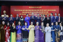 Party General Secretary To Lam and his spouse, staff of the Vietnamese Embassy and representatives of the Vietnamese community in a group photo at their meeting in Vientiane on December 1 evening. (Photo: VNA)