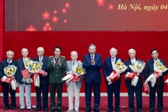 Party General Secretary To Lam (fourth, right) and Minister of Public Security General Luong Tam Quang (fourth, left) present flowers and gifts to former public security officers. (Photo: VNA)