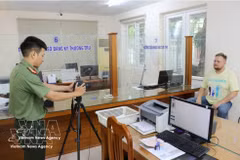 An immigration officer takes a photo of a foreigner as part of procedures to provide a Level-2 electronic identification account. (Photo: VNA)