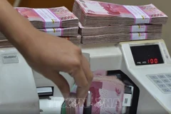 An employee at a foreign exchange office counts Indonesian rupiah banknotes. (Photo: AFP/VNA)