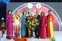 Ambassador Nguyen Dac Thanh presents flowers to President of the Vietnamese Businesswomen Association in Europe Trinh Thi Mui. (Photo: VNA) 