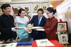 Prime Minister Pham Minh Chinh and his visiting Thai counterpart Paetongtarn Shinawatra contemplate and experience unique handicraft products of Vietnam on May 15. (Photo: VNA)