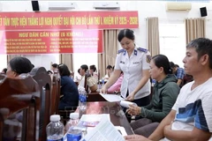 Officers of Coast Guard Region 4 distribute information leaflets to local fishermen. (Photo: VNA)