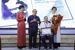 VNA General Director Vu Viet Trang (first, left) presents the Cricket Knight Award to composer Pham Tuyen (sitting) at the ceremony. (Photo: VNA)