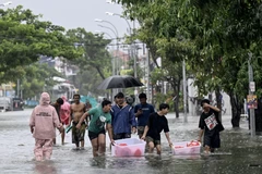 People move their belongings through an inundated street amid floods following heavy rain in Indonesia's resort island of Bali on February 24, 2026. (Photo: AFP)