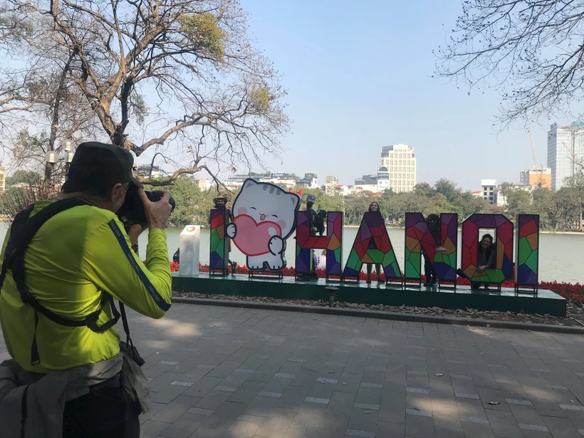 Foreign tourists take photos at Hoan Kiem Lake (Photo: daidoanket.vn)