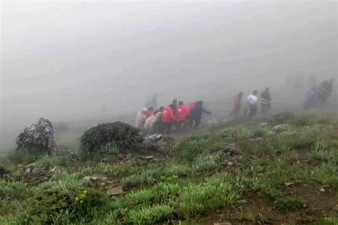 This grab taken from handout video footage released by Iranian Red Crescent Society (IRCS) on May 20, 2024 shows rescuers recovering bodies at the site of President Ebrahim Raeisi's helicopter crash in a fog-shrouded mountainous area of northwest Iran. (Photo: AFP/VNA) 