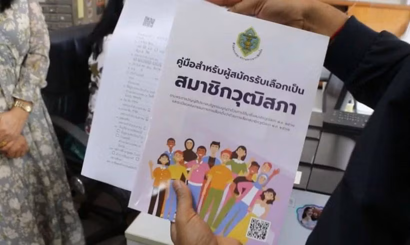 An official gives a senator candidate handbook and an application form to a woman applying for the senate election at Khon Kaen's registration office in Muang district on May 10. (Photo: Bangkokpost.com) 