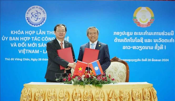 Vietnamese Minister of Science and Technology Huynh Thanh Dat (L) and Lao Minister of Technology and Communications Boviengkham Vongdara exchange the minutes of the first session of the Vietnam-Laos Committee for Cooperation in Technology and Innovation in Vientiane, Laos, on May 28. (Photo: VNA)