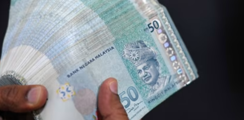 A money changer counts Malaysian ringgit banknotes for customers in Kuala Lumpur. (Photo: AFP)