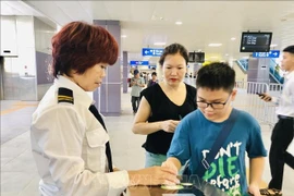 Hanoi Metro staff assist passengers at the ticket gate. (Photo: VNA)