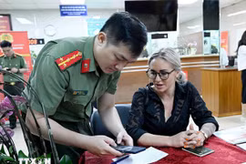 A police officer instructs a foreigner how to register for a level-2 electronic identification account. (Photo: VNA)