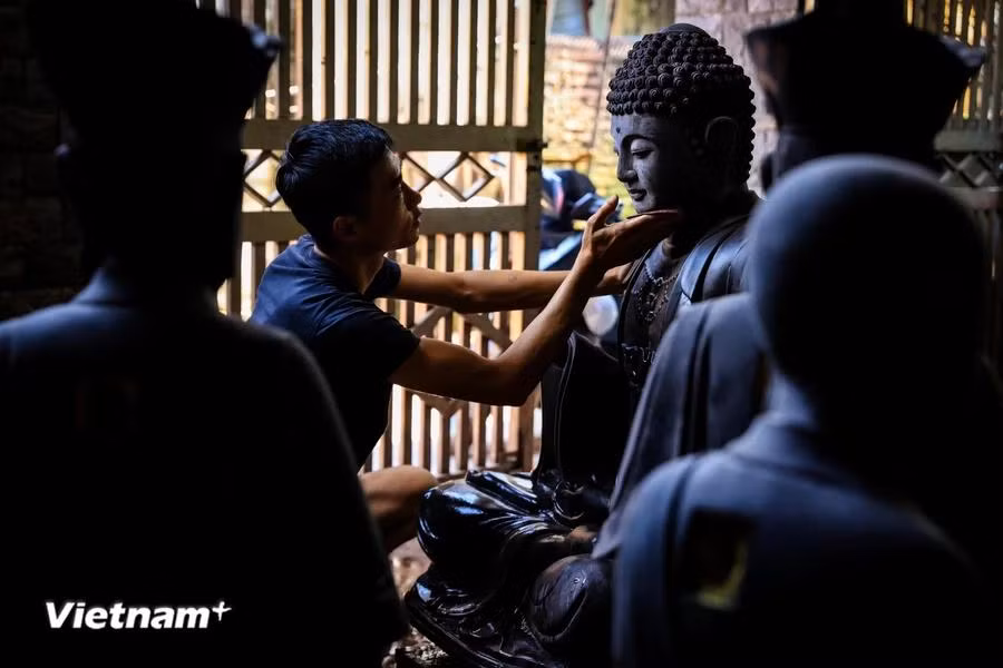Local villagers work tirelessly on wood pieces to create Buddha statues. (Photo: VietnamPlus)