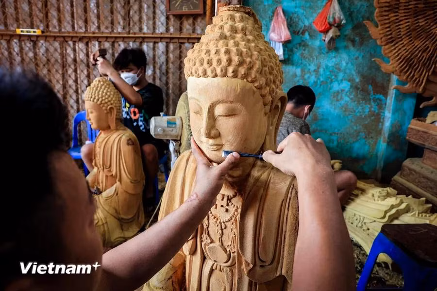 After many years of learning the craft from his father, Dai now has his own workshop producing wooden Buddha statues. (Photo: VietnamPlus)