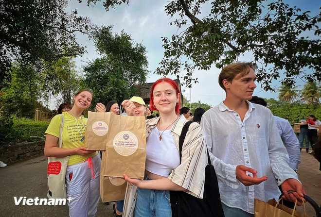 Foreign tourists receive souvenirs after experiencing Duong Lam ancient village in Hanoi's Son Tay district. (Photo: VietnamPlus) langcoduonglam.webp