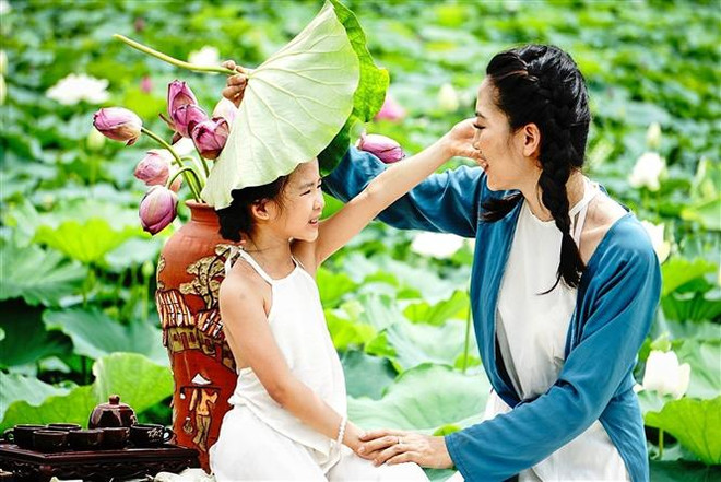 Mother and daughter capture a beautiful memory with blooming lotuses in May. (Photo: VNA) vna_potal_elegant_beauty_of_west_lake’s_blooming_lotus_7413296.jpeg