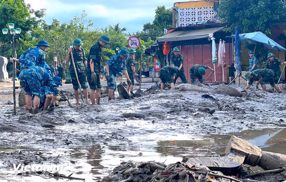 From early morning, hundreds of officers and soldiers are mobilised by the army to clear mud in the ancient streets of Hoi An, Da Nang city. (Photo: VietnamPlus)