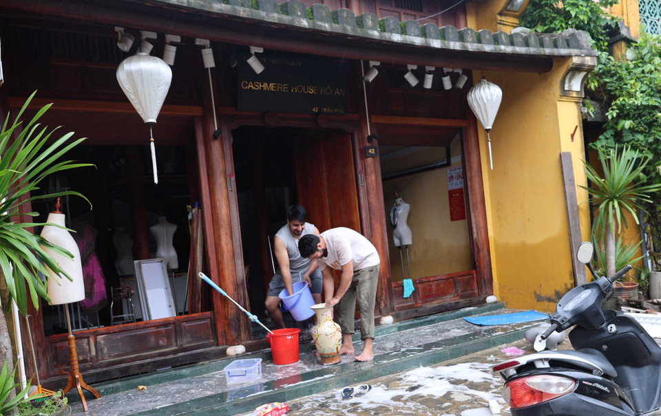 Foreign tourists staying in Hoi An join local residents in cleaning up after the floods. (Photo: VNA)
