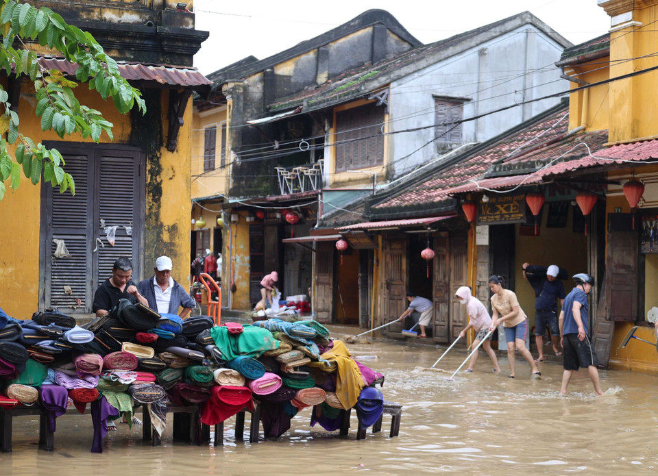 Residents clear mud at the Nguyen Thai Hoc – Le Loi intersection in Hoi An ward. (Photo: VNA)