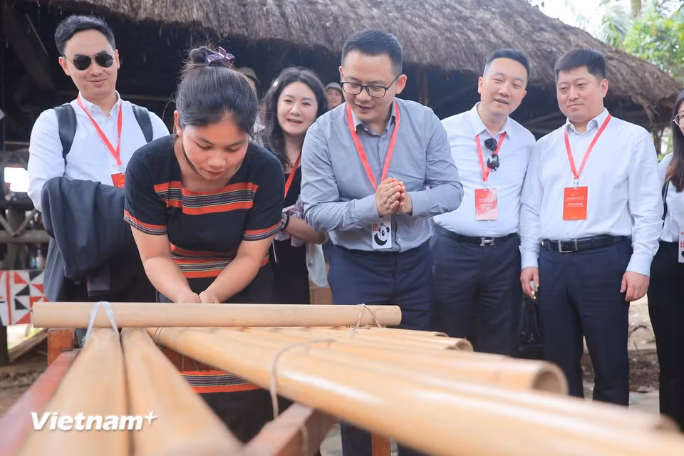 Visitors learn how to play the K’long put, a musical instrument of the Xo Dang people and several other ethnic groups in the Central Highlands. (Photo: VietnamPlus)
