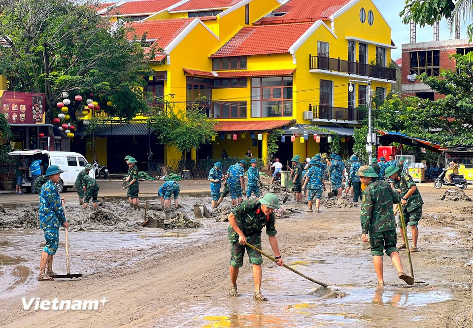 More than 400 officers and soldiers divided into multiple teams, coordinating by street sections to shovel mud and collect rubbish on the spot. (Photo: VietnamPlus)