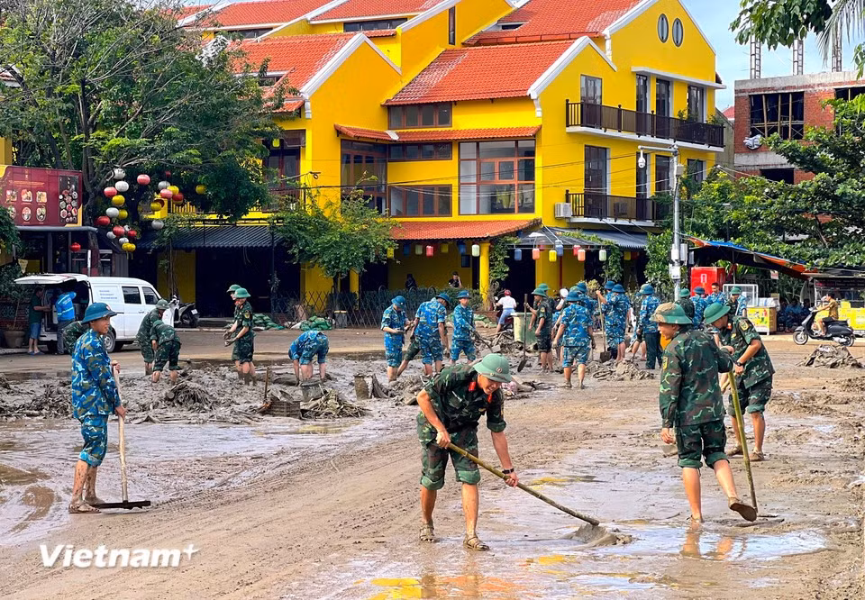 More than 400 officers and soldiers divided into multiple teams, coordinating by street sections to shovel mud and collect rubbish on the spot. (Photo: VietnamPlus)