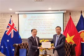 Ambassador Pham Hung Tam (R) hands over 12,700 AUD (8,700 USD) to the delegation to help victims of Typhoon Yagi (Photo: VNA)
