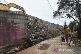 Two residents pass beside the boundary wall of the Burangkeng Final Disposal Site (TPA) which was damaged by a landslide in Bekasi Regency, West Java, November 12. (Photo: Antara/ Fakhri Hermansyah/rwa) 