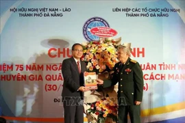 A representative of the Da Nang liaison board of the Vietnamese volunteer soldiers and military experts in Laos presents the 75th anniversary commemorative book to Lao Consul General in Da Nang Souphanh Hadaoheuang at the ceremony. (Photo: VNA)