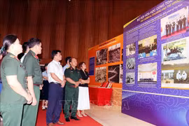 Visitors look at photos at the exhibition (Photo: VNA)
