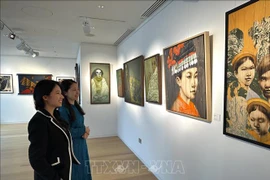 A staff of Thang Long Art Gallery staff introduces artworks to a visitor at the exhibition. (Photo: VNA)